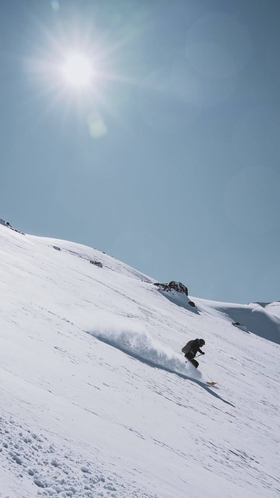 Skier descending an untouched snow-covered Andean slope leaving powder tracks